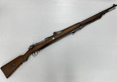 un fusil avec un canon en bois sur une surface blanche