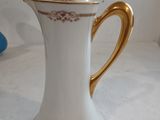 a white and gold coffee pot with a gold handle