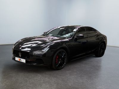 une voiture de carnaval noire garée dans une pièce blanche au sol noir