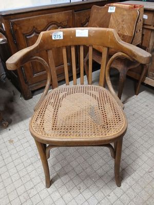 a wooden chair with a woven seat in the middle of a room