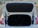 the back of a white car with its trunk open on the road