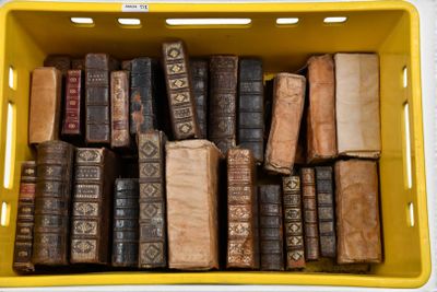 a yellow basket full of old books on a table