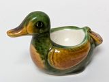 a green and brown duck shaped teapot on a white surface