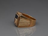 a close up of a gold ring with a black stone on it