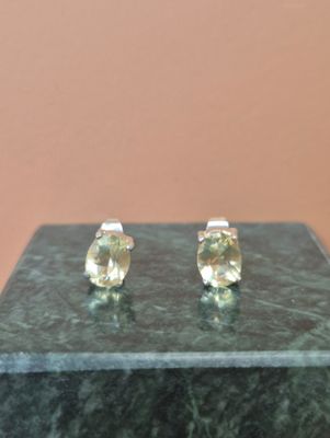 une paire de boucles d'oreilles à clous en saphir jaune posées sur une surface en marbre vert
