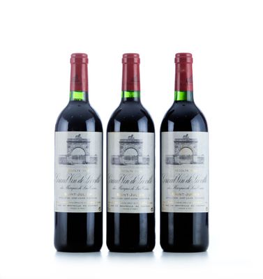 trois bouteilles de vin rouge posées l'une à côté de l'autre sur une surface blanche