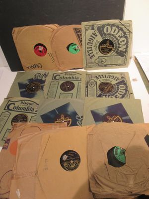 une boîte remplie de disques et une paire de ciseaux posés sur une table