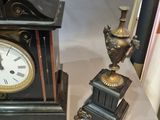 a clock and a vase on a table next to each other