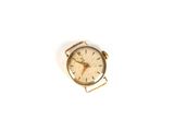 une petite montre en or posée sur une surface blanche, sur fond blanc
