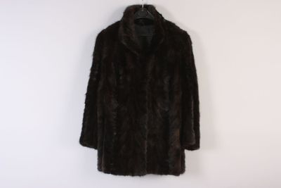 a black fur coat hanging on a white wall next to a coat rack