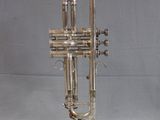 silver plated trumpet on stand on grey background