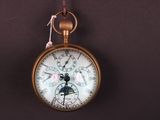 une montre de poche accrochée au mur avec un ruban rose