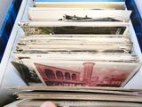 a person holding a stack of old records in a blue box