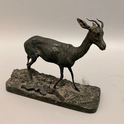 statue en bronze représentant un cerf posé sur un rocher, sur fond blanc