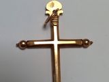 une croix dorée posée sur une table blanche sur laquelle se trouve une croix dorée