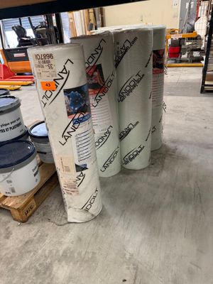 Plusieurs rouleaux de papier sont empilés les uns sur les autres dans un entrepôt
