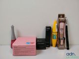 a box of mascara, mascara brush, eyeliners, and other cosmetics items on a table
