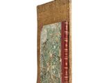 an old book with a red cover sitting on top of a white surface