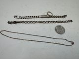 two silver bracelets and a coin on a white surface