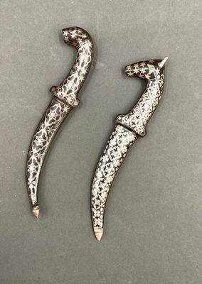 une paire de boucles d'oreilles en métal argenté et noir posées sur une surface grise