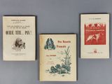 Trois livres sont alignés sur une table devant un fond bleu.