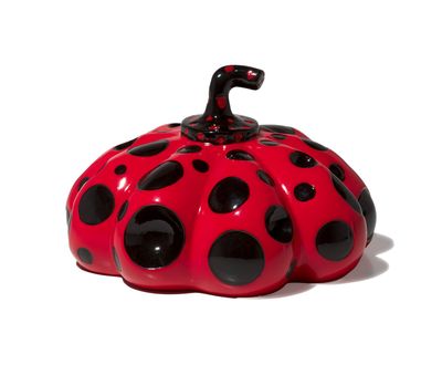 a small red and black pumpkin on a white surface