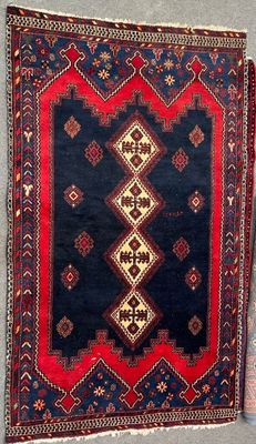 un tapis bleu et rouge accroché au mur, à côté d'un mur