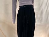 Le mannequin porte une jupe noire et un pull à col roulé gris.