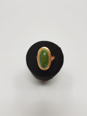 a close up of a ring with a green stone in it