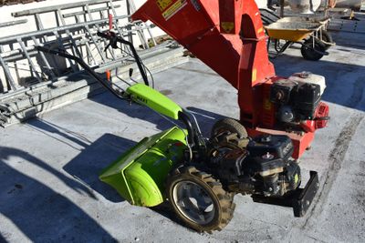 a green and red tractor and a red machine on the ground