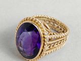 gros plan d'une bague en or avec une pierre violette