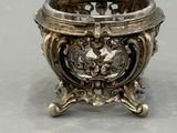 an antique silver plated bowl on a stand with a flower decoration