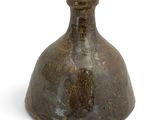 un vase brun posé sur une surface blanche