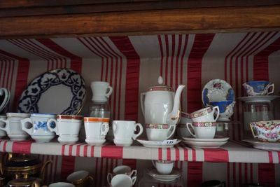 de nombreuses tasses et soucoupes posées sur une étagère dans un vaisselier
