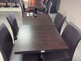 une table et des chaises dans une pièce avec beaucoup de fenêtres
