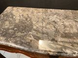 a marble top table with a wooden base on a tile floor