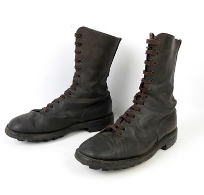 une paire de bottes en cuir noir avec des lacets marron sur fond blanc