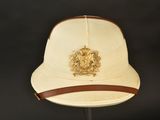 beige hat with a leather band and a crest on the front