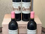 four bottles of red wine sit in a wooden crate on a table