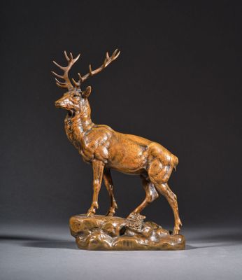 une sculpture en bronze représentant un cerf debout au sommet d'un rocher