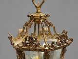 an antique brass hanging light fixture with a bird on top
