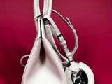 a white purse with a heart shaped handle on a red background