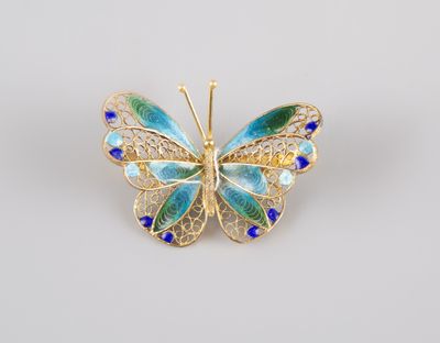une broche en forme de papillon bleu et vert sur fond blanc