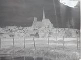 black and white photograph of a small village with a church in the background