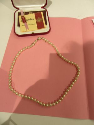a pearl necklace on a pink table next to a pink book
