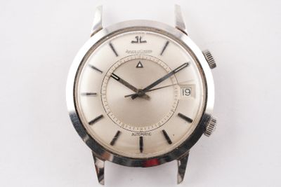 une montre argentée posée sur une surface blanche, sur fond blanc