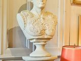 un buste d'homme assis sur un socle dans un coin de la pièce