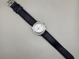 gros plan d'une montre sur une surface blanche avec un bracelet noir