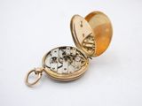 a gold pocket watch that is open on a white surface