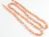 a close up of an orange beaded necklace on a white surface